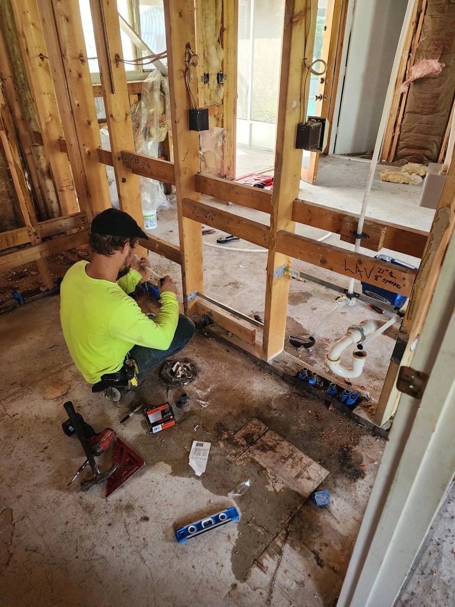 Plumber setting drain and supply rough-in for a bathroom during new construction framing