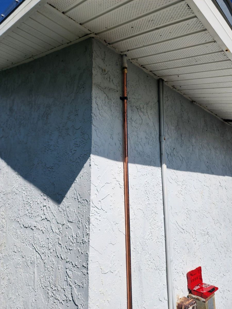 New copper water line routed up an exterior stucco wall on a residential repipe