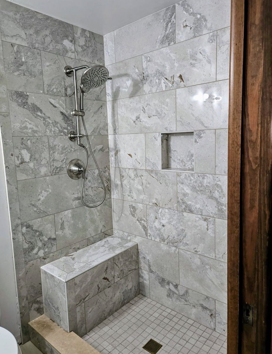 Custom tiled walk-in shower with a bench and niche