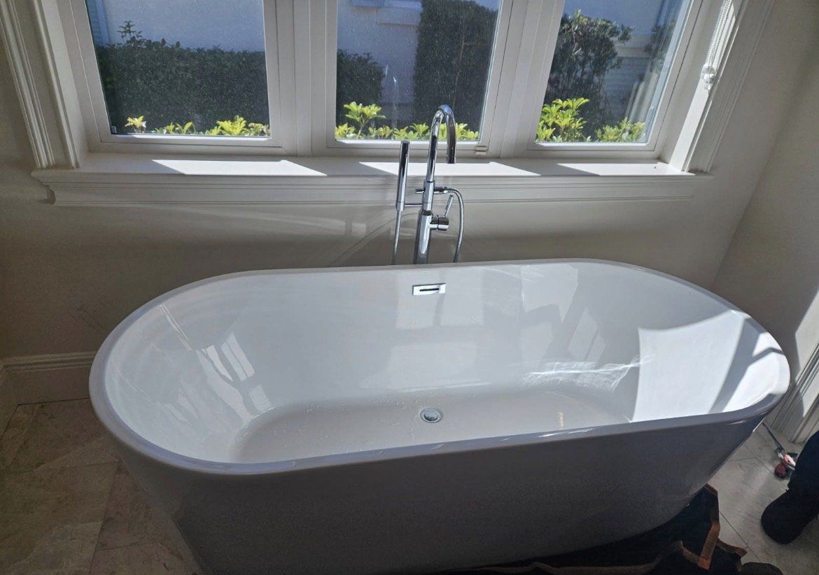 Freestanding bathtub with a floor-mounted tub filler near a window